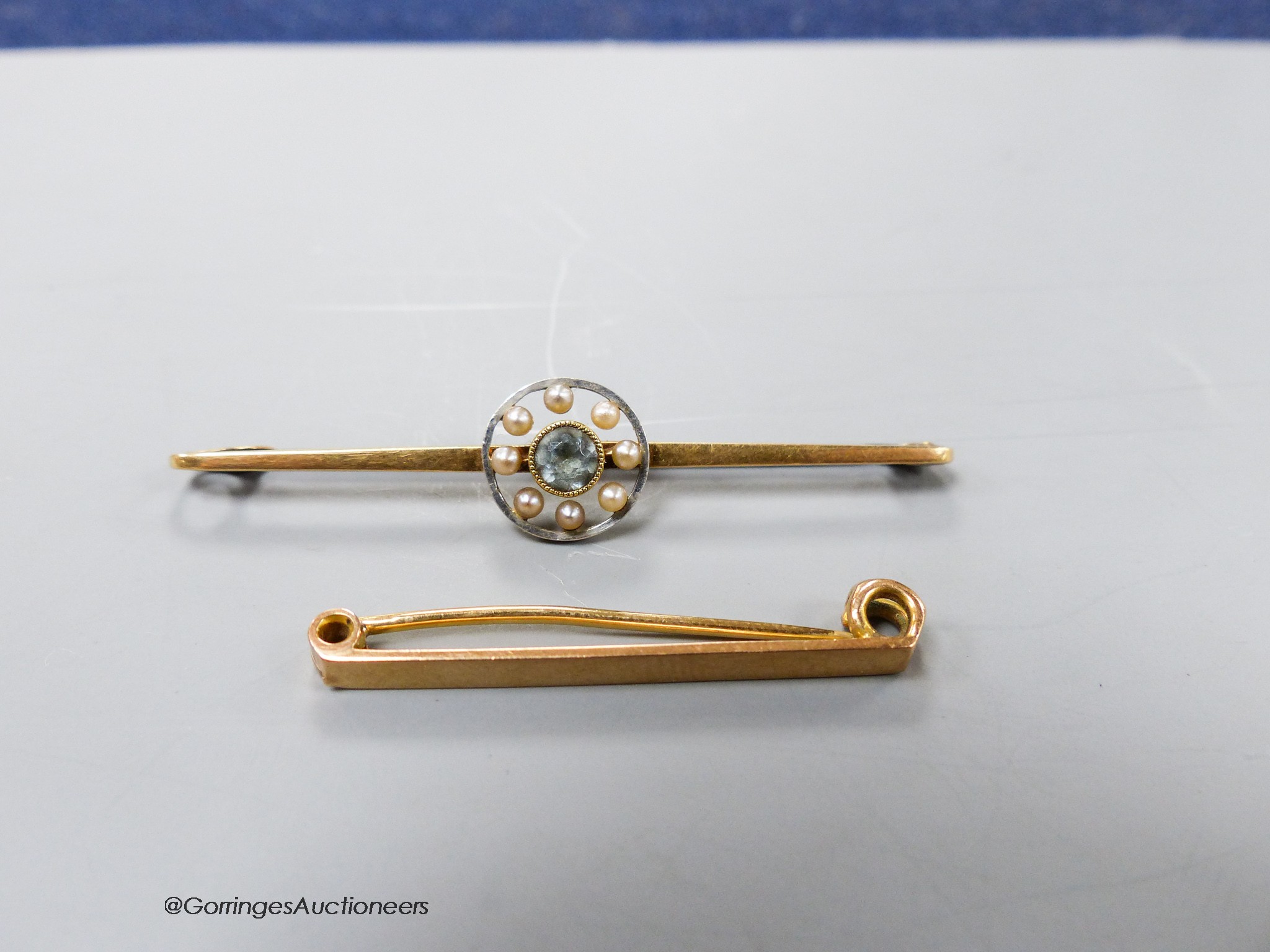An Edwardian 15ct, aquamarine and seed pearl set bar brooch, 56mm, gross 3.5 grams and a 9ct bar brooch, 2 grams.
